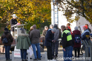 Ein Podium mit Redner, darum stehen TeilnehmerInnen