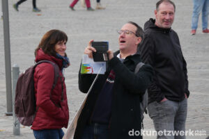 Zu sehen ist Dr. Christian Steidl. Er lehnt sich zurück, um den Gegenprotest mit seinem Handy abzufotografieren