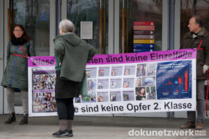 Drei Personen mit einem Transparent, dass deutsche Opfer vermeintlicher Gewalttaten von Zuwanderern zeigen soll