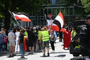 Als der Demozug durch die Blockade ins Stocken gerät, packen Teilnehmende schwarz-weiß-rote Flaggen aus